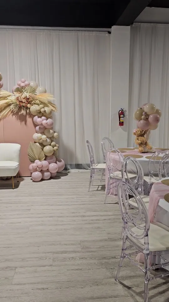 Event room set with pink and white balloon installations and round tables
