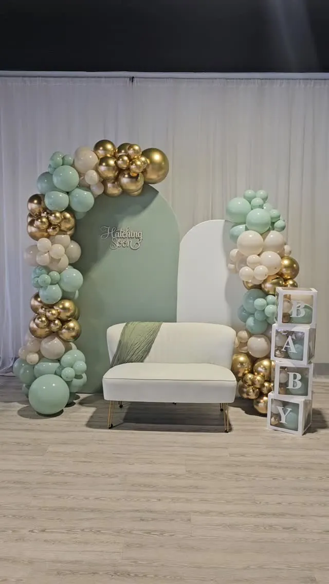 Sage and gold balloon arch behind a white loveseat