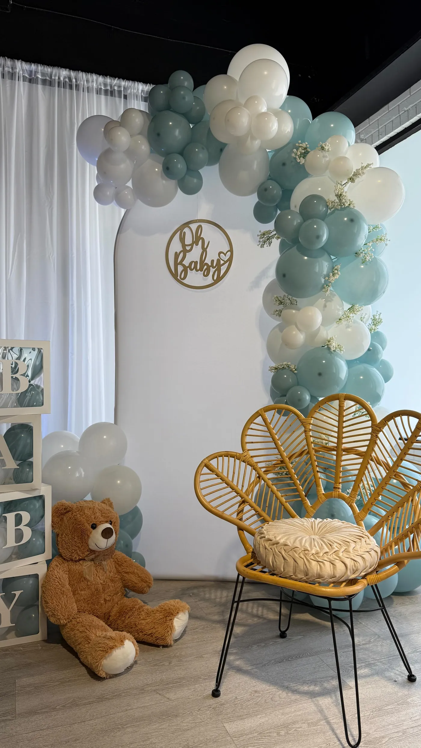 Teddy bear baby shower balloon arch with a rattan peacock chair
