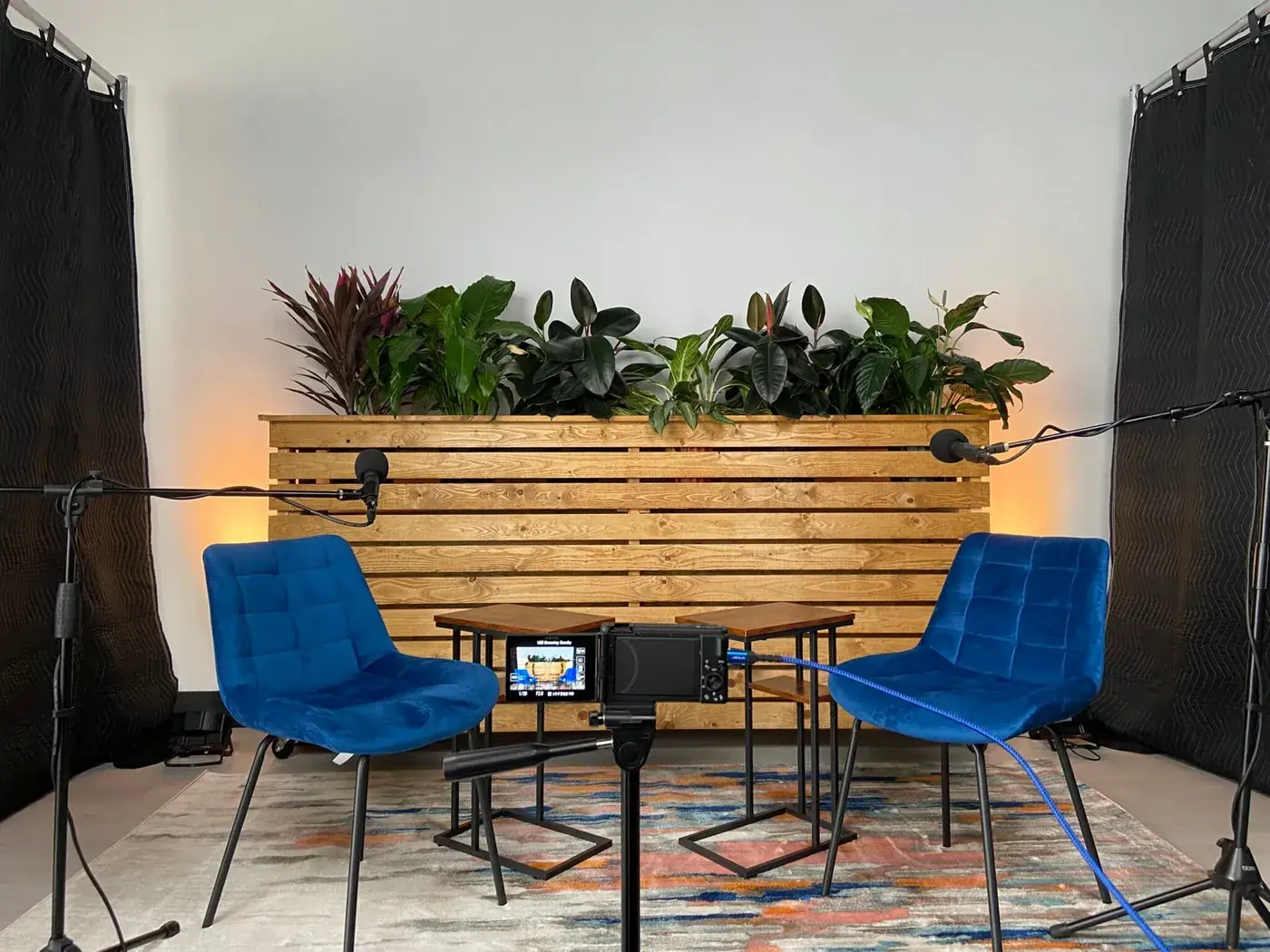 Podcast setup with two blue chairs, microphones and a wood slat backdrop at Event Center Miami